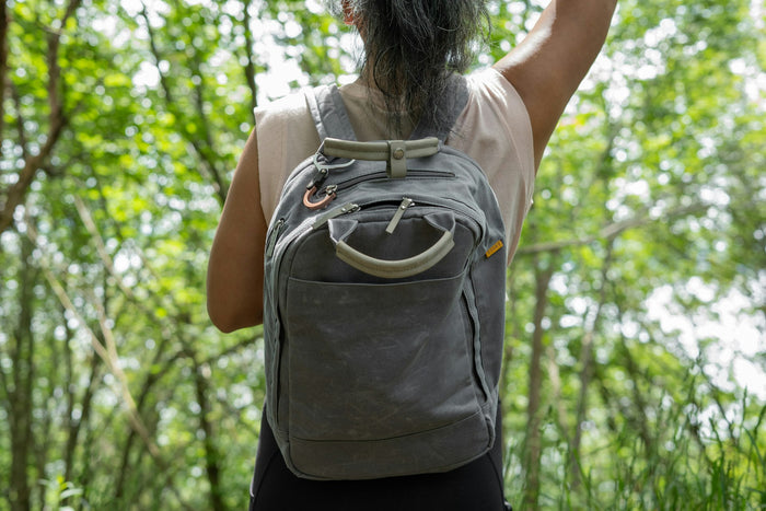 Woman wearing backpack walking through green forest representing active on-the-go lifestyle