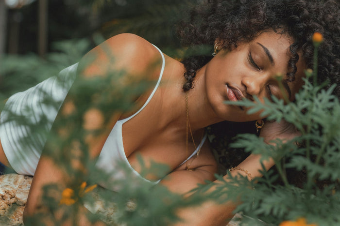 Woman relaxing peacefully among lush green botanical plants representing natural vaginal wellness